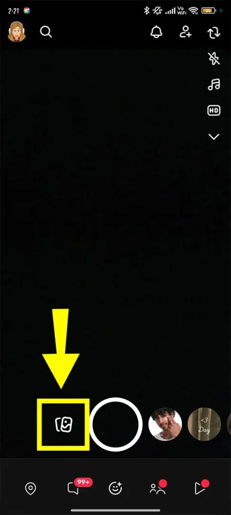 Tapping the Snapchat Memories icon (the double-wrapped rectangles) located at the bottom of the camera screen to access saved Snaps.